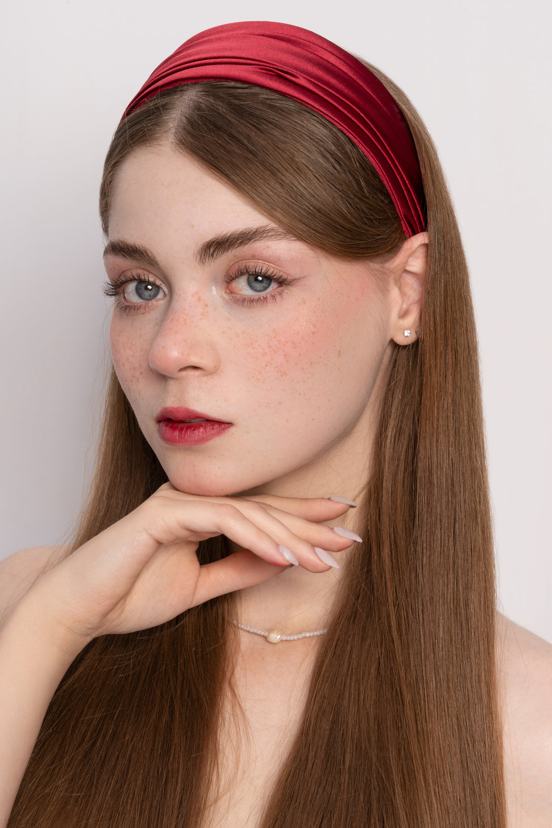 Woman wearing a red headband with a plain background