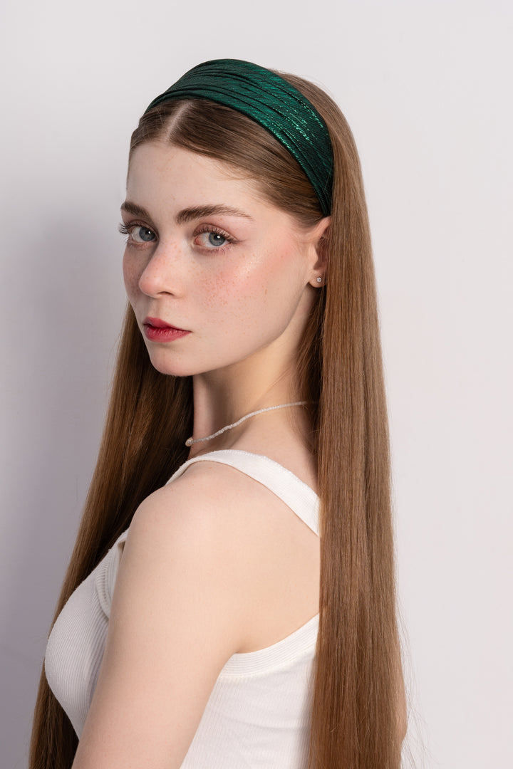 Woman wearing a green headband against a plain background